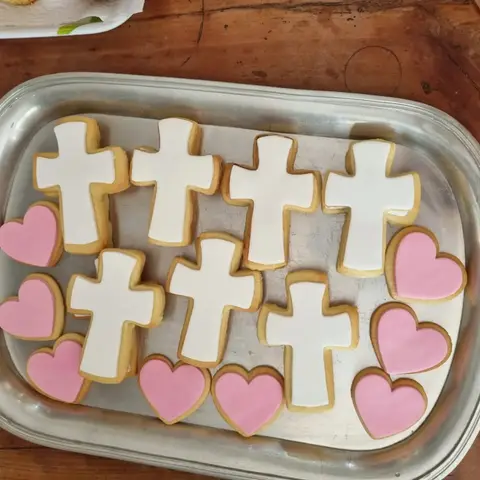 Sablés glacés en forme de croix blanches et de cœurs roses, sur un plateau