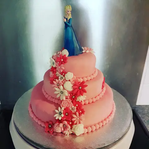 Gâteau corail à trois étages, cascade de fleurs en sucre et figurine de la Reine des neiges