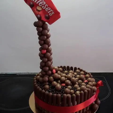 Gâteau entouré de biscuits au chocolat, un sachet de billes chocolatées suspendu au-dessus