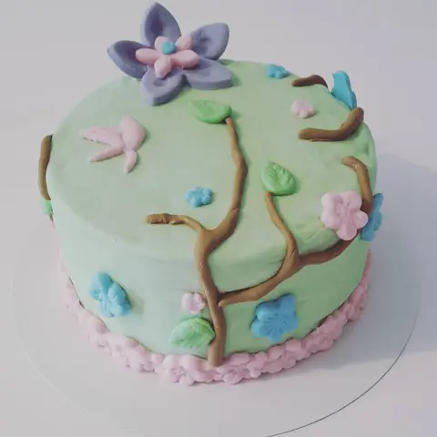 Gâteau vert d'eau décoré d'une branche fleurie et d'oiseaux en pâte à sucre
