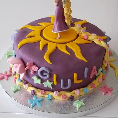 Gâteau violet orné d'un grand soleil jaune et d'une figurine de princesse à longue tresse