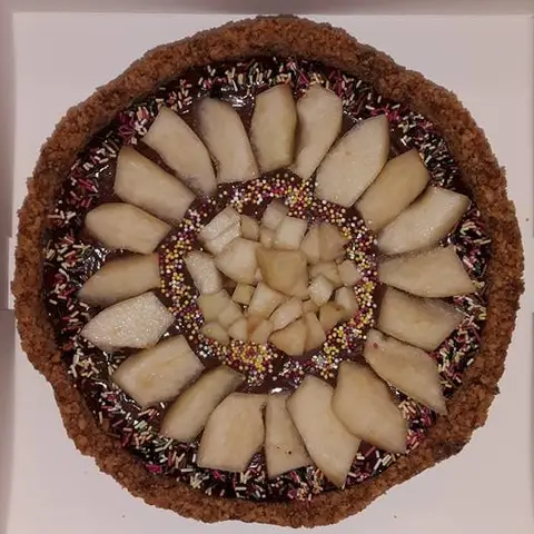Tarte au chocolat garnie de lamelles de poire en rosace et de vermicelles colorés