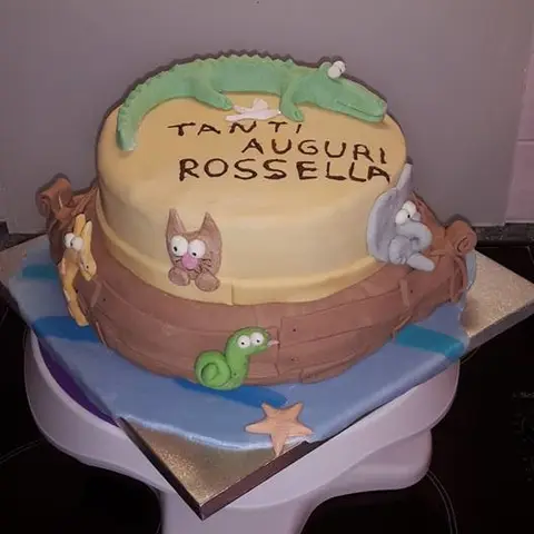 Gâteau en forme de bateau en bois avec un crocodile, un chat et un escargot en pâte à sucre
