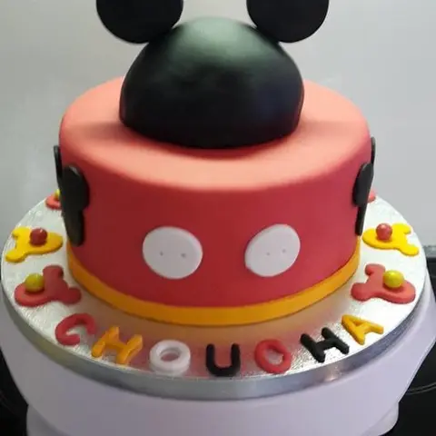 Gâteau rouge à boutons blancs surmonté de deux grandes oreilles noires de Mickey