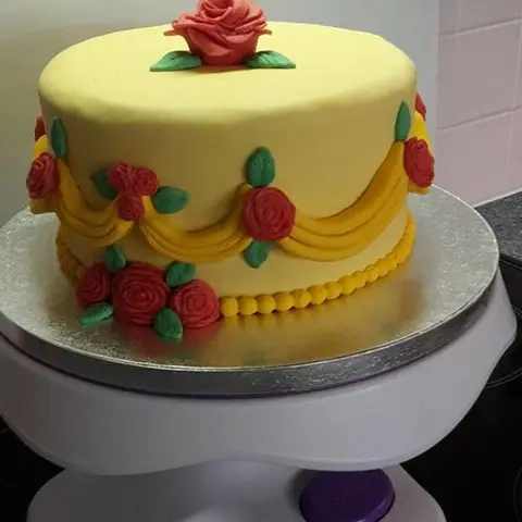 Gâteau jaune décoré de drapés et de roses rouges en pâte à sucre