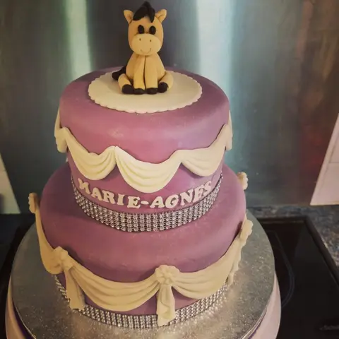 Gâteau violet à deux étages avec des drapés crème et un petit cheval au sommet