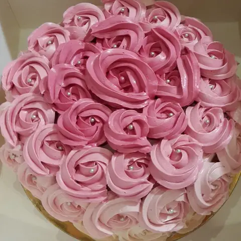 Gâteau entièrement couvert de rosaces de crème rose
