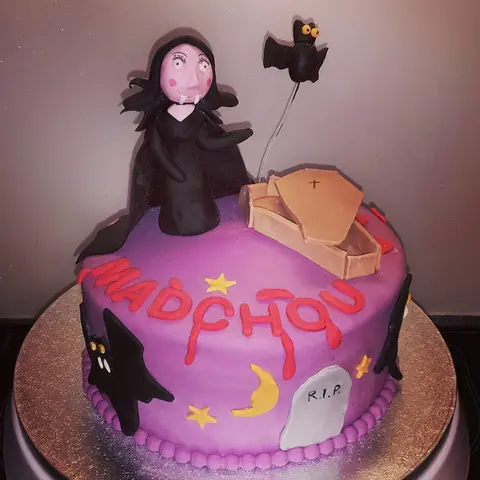 Gâteau violet d'Halloween avec un personnage en cape noire, un cercueil et une chauve-souris