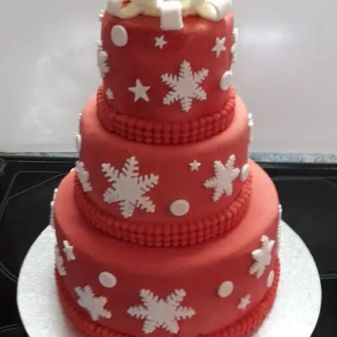 Gâteau rouge à trois étages décoré de flocons de neige blancs