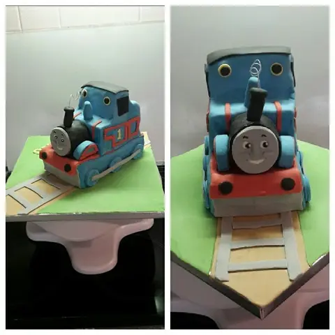 Gâteau en forme de locomotive bleue de Thomas le petit train sur ses rails, vu sous deux angles