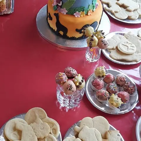 Table de fête avec un gâteau aux animaux de la savane, des sablés et des cake pops