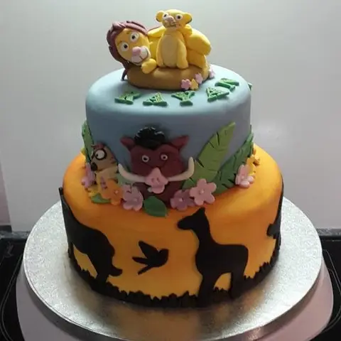 Gâteau à deux étages bleu et orange avec les personnages du Roi lion et des silhouettes d'animaux