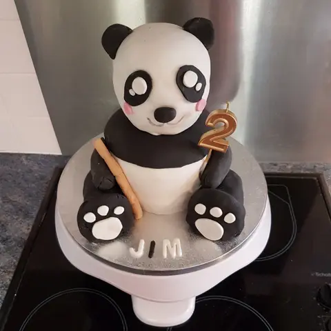 Gâteau en forme de panda assis tenant une bougie en forme de 2