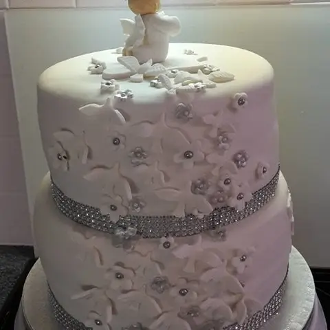 Gâteau gris perle à deux étages couvert de petites fleurs en relief, ceinturé d'un ruban brillant