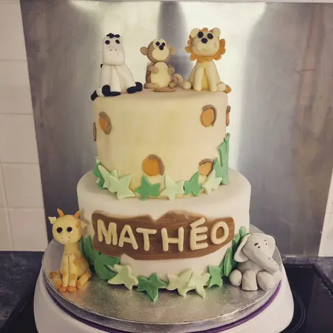 Gâteau beige à deux étages avec un zèbre, un singe, un lion, une girafe et un éléphant