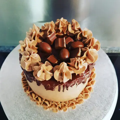 Gâteau au chocolat et au caramel couronné de crème pochée et de bonbons au chocolat