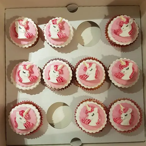 Cupcakes décorés de têtes de licorne roses, rangés dans une boîte