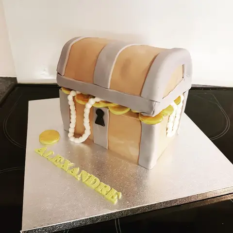 Gâteau en forme de coffre au trésor d'où débordent des perles et des pièces d'or