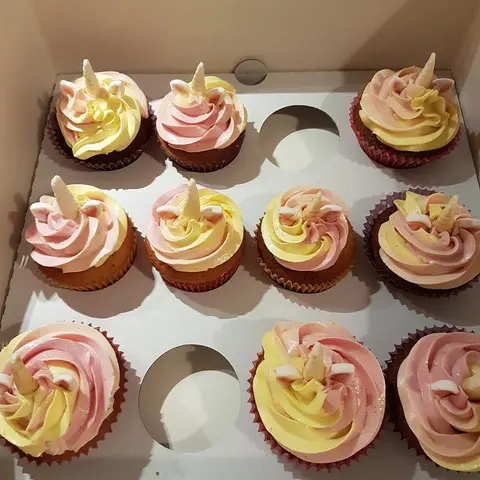 Cupcakes à la crème rose et jaune surmontés d'une petite corne de licorne