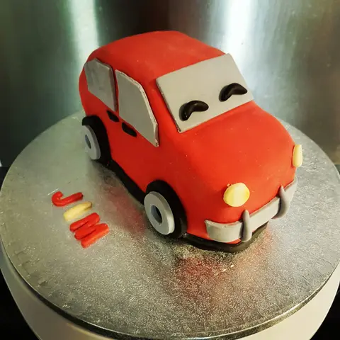 Gâteau en forme de petite voiture rouge aux yeux rieurs