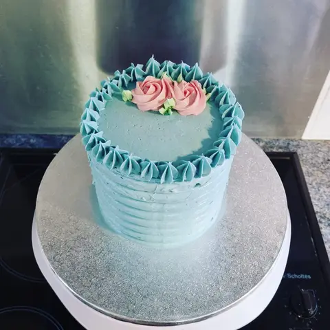 Petit gâteau à la crème bleue strié, couronné de roses pochées
