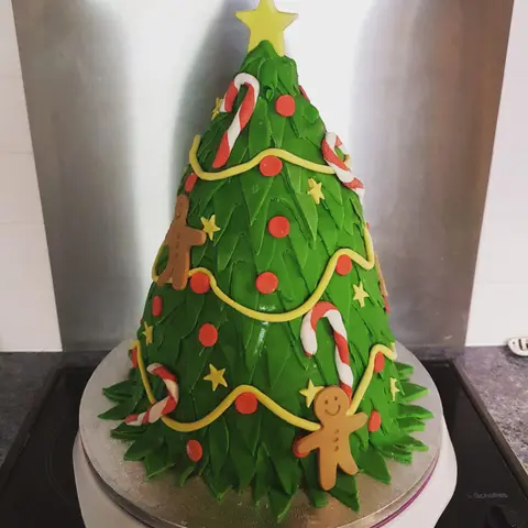 Gâteau en forme de sapin de Noël vert avec guirlande, sucres d'orge et bonshommes de pain d'épices