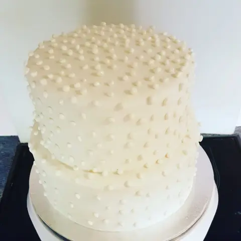 Gâteau blanc à deux étages entièrement couvert de petites perles en sucre