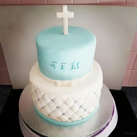 Gâteau bleu ciel et blanc à deux étages, effet matelassé, surmonté d'une croix blanche