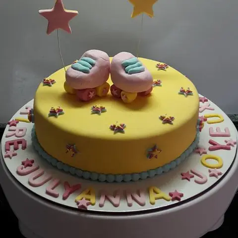 Gâteau jaune décoré d'étoiles, avec une paire de patins à roulettes pastel au sommet
