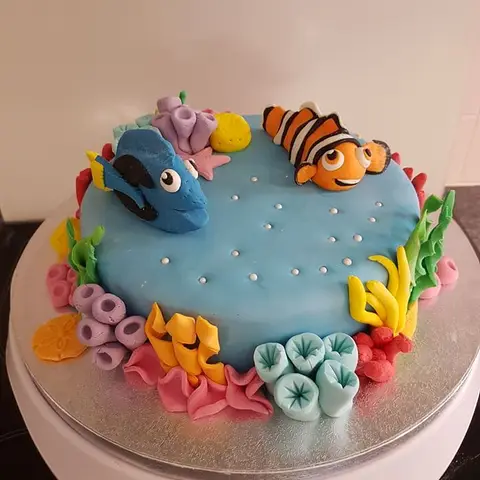 Gâteau bleu bordé de coraux colorés, avec un poisson-clown et un poisson bleu