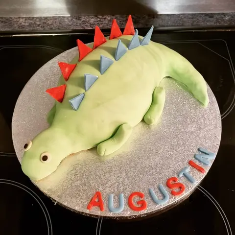 Gâteau en forme de crocodile vert à crête rouge et bleue
