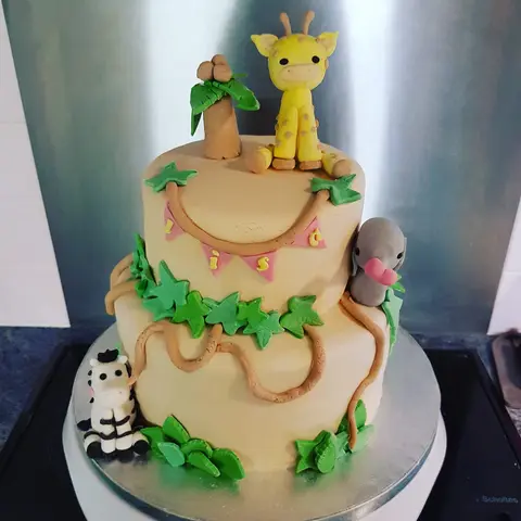 Gâteau beige à deux étages avec une girafe, un zèbre, un palmier et une guirlande de fanions