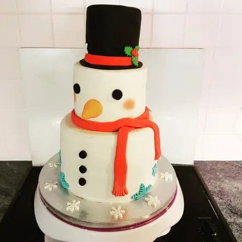 Gâteau en forme de bonhomme de neige, chapeau haut de forme noir et écharpe rouge
