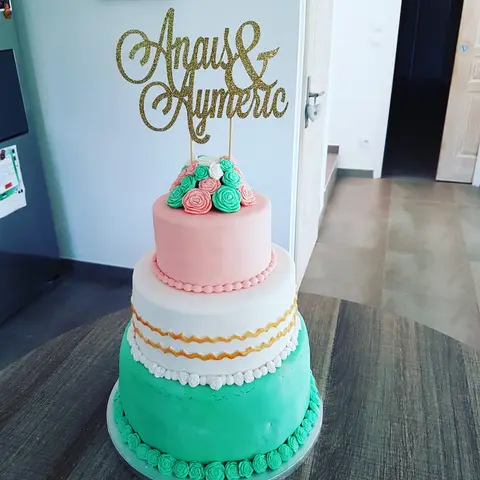 Gâteau de mariage à trois étages vert d'eau, blanc et rose, surmonté de roses