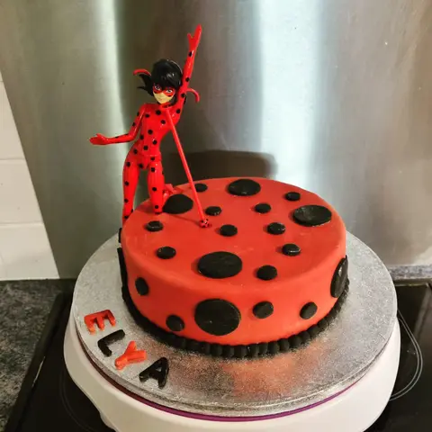 Gâteau rouge à pois noirs surmonté d'une figurine de Ladybug