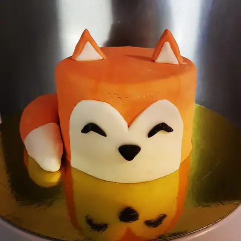 Gâteau en forme de renard roux aux yeux rieurs, la queue enroulée