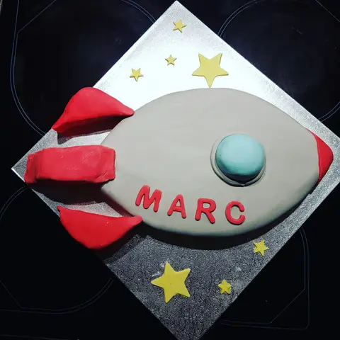Gâteau en forme de fusée grise et rouge entourée d'étoiles