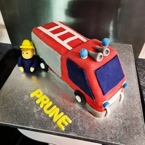 Gâteau en forme de camion de pompiers rouge avec Sam le pompier à côté