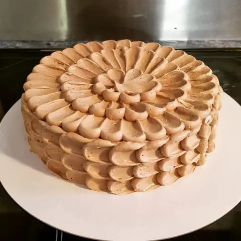 Gâteau couvert de pétales de crème au caramel pochés en rosace