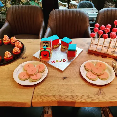 Table d'anniversaire avec un train en pâte à sucre rouge et bleu, des sablés au chiffre 5, des cupcakes et des cake pops rouges