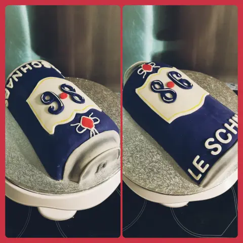 Gâteau en forme de canette bleu marine couchée, à étiquette blanche marquée 8.6 et inscription en lettres blanches