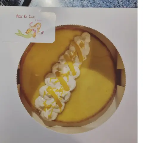 Tarte au citron dorée vue du dessus, garnie d'une tresse de meringue et de zestes de citron