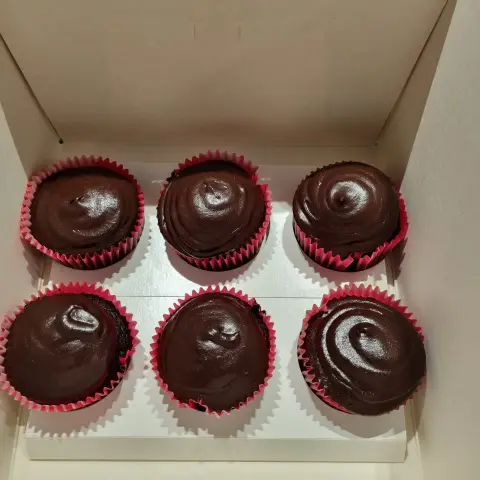 Six cupcakes au chocolat nappés d'un glaçage brillant en spirale, dans des caissettes rouges