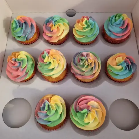 Dix cupcakes coiffés d'une crème en rosace mêlant rose, jaune, vert, bleu et violet