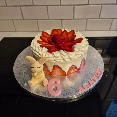 Fraisier rond couronné de fraises et de crème, un lapin crème assis à côté, avec un 6 et un prénom roses