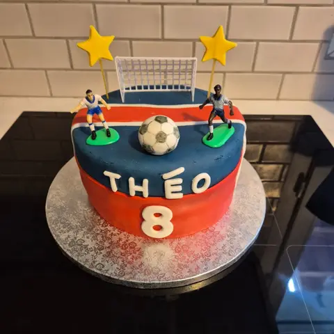 Gâteau bleu marine et rouge avec cage de but, deux footballeurs, un ballon et deux étoiles jaunes, prénom et 8 blancs